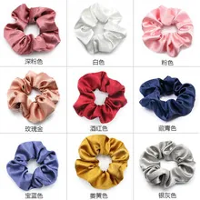 Detail showing various colors of satin silk scrunchies with smooth glossy texture