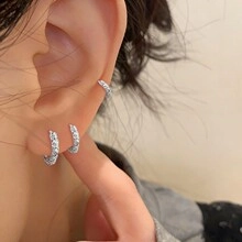 Detailed macro view of silver hoop earrings set with zircon micro-pave on the ear