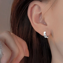Close-up of elegant silver hoop earring with scalloped edges worn by a model