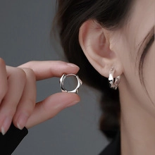 Macro shot of silver irregular lava texture hoop earrings with minimalist ripple design