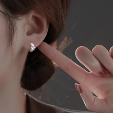 Macro close-up of silver hoop earring with marquise-cut zircon on a model's ear