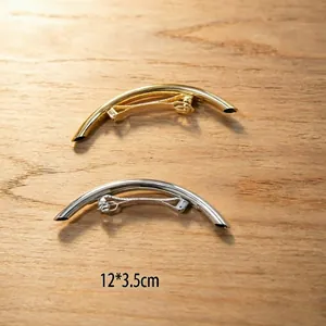Polished gold and silver curved spring hair clips set on light wood background