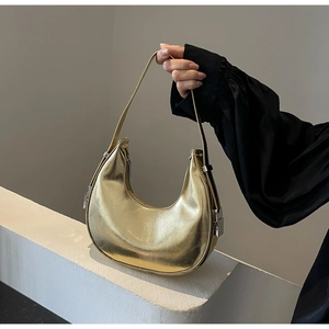 Close-up of metallic gold crescent underarm bag with silver buckle and sleek texture