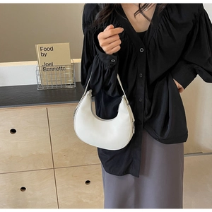 Close-up of a white leather crescent shoulder bag with silver hardware for women