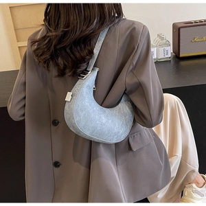 Detail showing light blue crescent hobo bag with adjustable strap on model shoulder