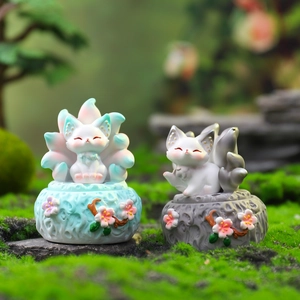 Detail view of two miniature Kunlun nine-tailed fox resin figurines on mossy bases
