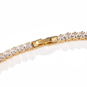 Close-up of gold-plated tennis chain with princess-cut cubic zirconia and fold-over clasp