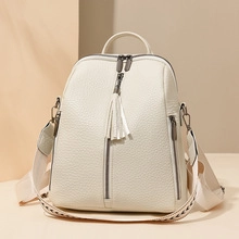 Close-up of litchi grain leather texture and tassel zipper detail on white backpack