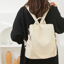Minimalist beige faux leather backpack shown on a model in a modern interior setting