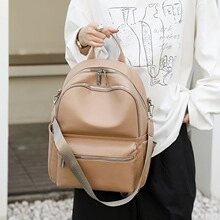 Outdoor model holding a large khaki PU leather laptop backpack with dual front pockets