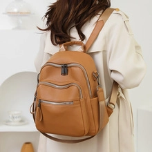 Side view of brown faux leather backpack with multiple zipper pockets and lychee texture