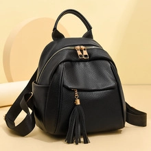 Detail of black pebbled leather backpack with gold zippers and tassel pendant on the front pocket