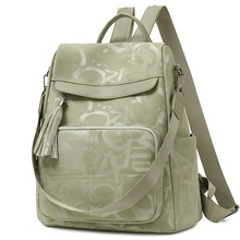 Detail view of sage green laptop backpack with letter graffiti and metal tassel charm