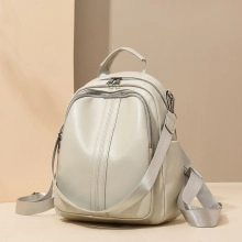 Close-up of the light gray leather backpack showing top handle and vertical decorative stitching