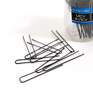 U-shaped black metal hairpins with ripple texture on white background and clear bottle