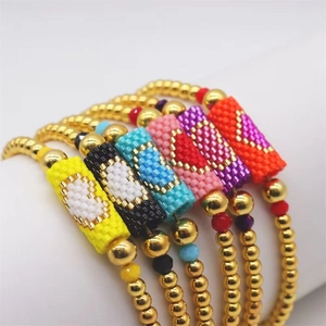 Macro shot of colorful handmade Miyuki bead heart bracelets with shiny gold beads