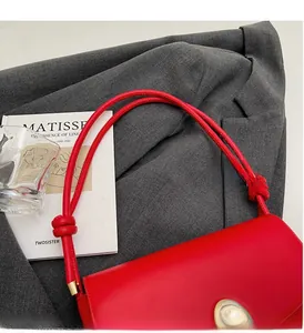 Detail of red leather handbag with unique gold metal clasp and knot handle design