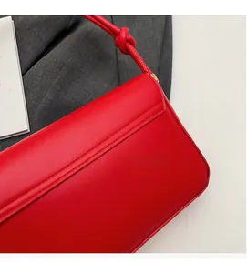 Close-up of a red leather handbag with knotted strap detail and fine stitching texture