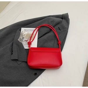Detailed back view of a red leather underarm bag with unique knotted strap on a blazer