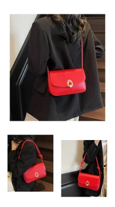 Detail of red leather crossbody bag featuring gold horseshoe buckle and knotted strap accents