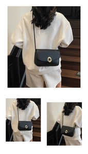 Detail of minimalist black crossbody bag with golden horseshoe-shaped metal buckle clasp