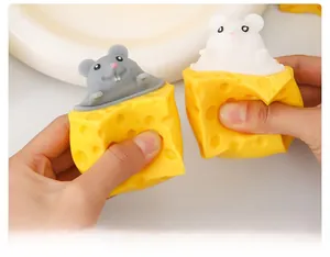 Detail showing hand squeezing a cute gray squirrel toy popping out of a yellow cheese cube