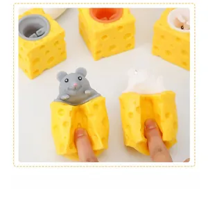Close-up of fingers squeezing a yellow cheese toy with a cute pop-up squirrel inside