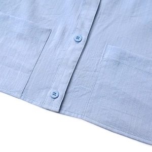 Detailed macro view of light blue shirt showing vertical texture, pocket, and neat stitching