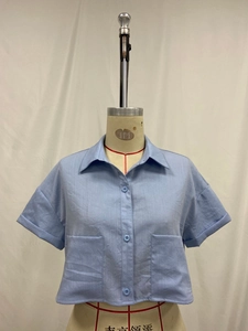 Detail view of light blue short-sleeved crop shirt with lapel and dual chest pockets