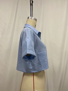 Detailed side view of light blue linen crop shirt showing fabric texture and pocket detail