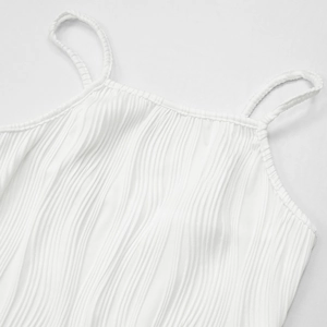 Close-up of white pleated knit fabric texture and thin straps on square neck camisole