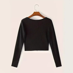 Dettaglio del crop top nero in maglia a coste a maniche lunghe su stampella in legno