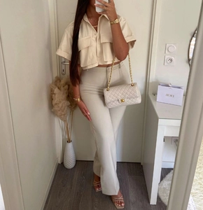 Detail of a beige short sleeve utility shirt with flap pockets and matching high waist pants
