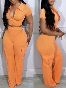 Detail eines orangefarbenen Rippstrick-Crop-Tops mit Ringreißverschluss und Cargo-Hose