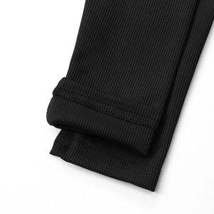 Detailed close-up of ribbed knit fabric texture and double-stitched hem on black dress