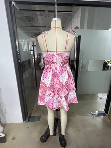 Detail eines rosa Blumenkleides mit gestuftem Rüschensaum und Schleifen-Schultergurten