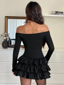 Elegante abito nero aderente a maniche lunghe con spalle scoperte e fondo a balze