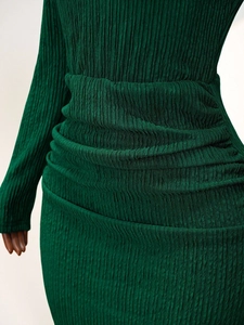Détail du tissu plissé vert foncé et taille froncée sur la robe à manches longues