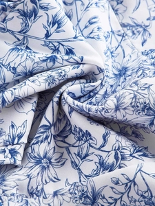 Close-up of vintage blue floral pattern on white fabric with detailed twill weave texture