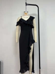 Detail view of the ruffle trim and high slit on the black asymmetric chiffon dress