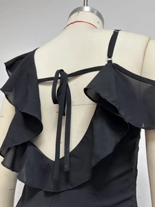 Detail of black chiffon dress featuring ruffled layers and adjustable back ties on a mannequin