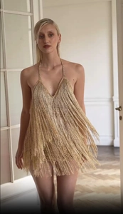 Détail de franges dorées et fil métallique sur une robe de soirée dos nu sexy