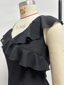 Detail of black one-shoulder dress showing ruffled neckline and smooth elastic fabric