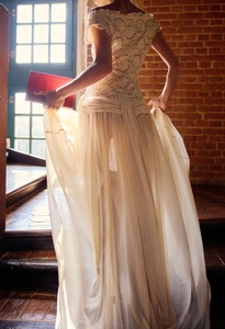 Detail of off-shoulder lace bodice and flowing chiffon skirt on elegant ivory evening dress