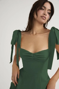Detail of emerald green chiffon dress featuring a square neckline and bow shoulder straps