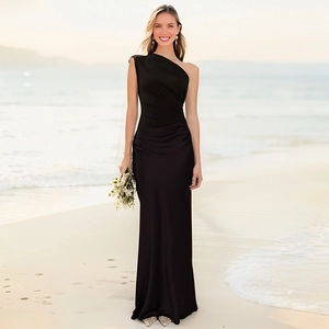 Close-up of elegant black one-shoulder satin maxi dress with waist pleats on beach