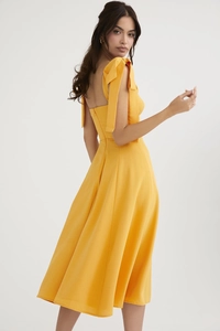 Detail of yellow backless dress featuring shoulder bow ties and a hidden zipper closure