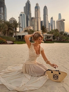 Detail of elegant V-neck lace top and flowing chiffon maxi skirt in beige resort style