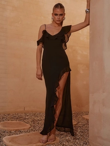 Sexy black chiffon dress with asymmetrical ruffles and high slit in a summer resort setting