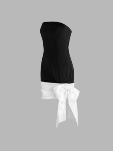 Detail eines eleganten zweifarbigen Satin-Kleides mit großer weißer Schleife und schwarzem Mieder